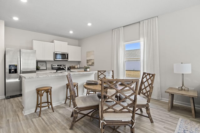 dining space with sink and light hardwood / wood-style flooring