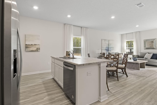 kitchen featuring a center island with sink, sink, white cabinetry, light hardwood / wood-style flooring, and appliances with stainless steel finishes