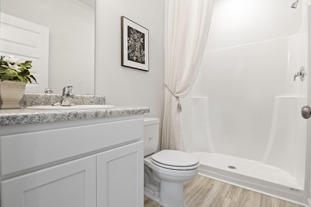 bathroom with toilet, vanity, hardwood / wood-style flooring, and curtained shower