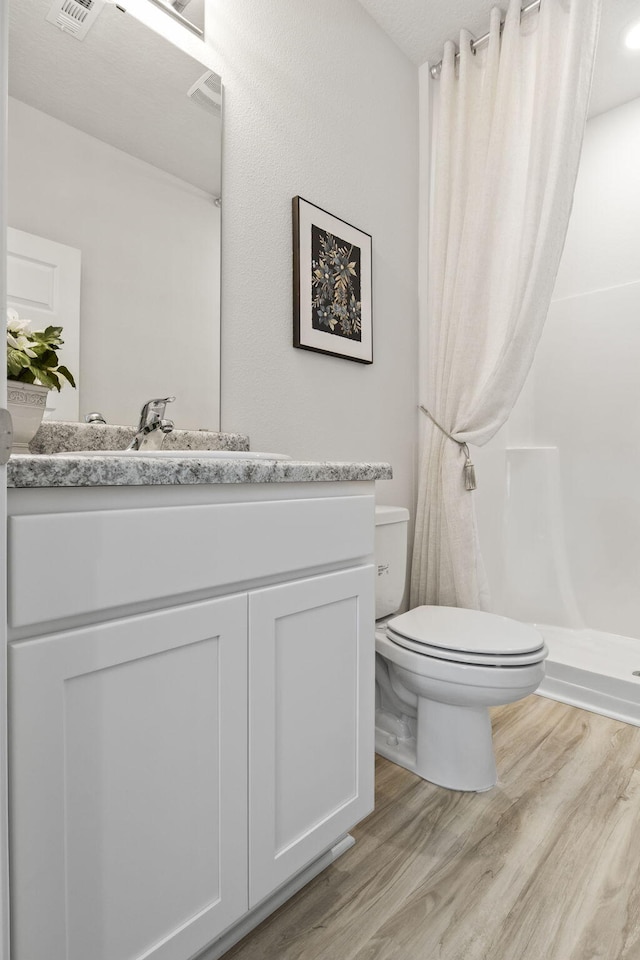 bathroom with toilet, walk in shower, wood-type flooring, and vanity