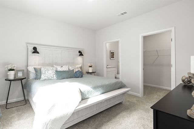 carpeted bedroom featuring ensuite bath, a walk in closet, and a closet