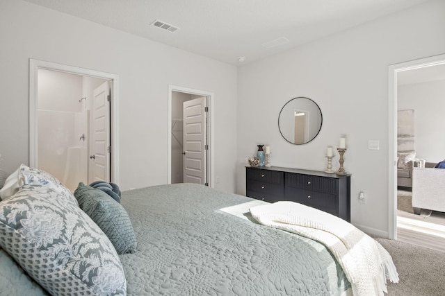 bedroom with ensuite bath, a walk in closet, a closet, and carpet flooring