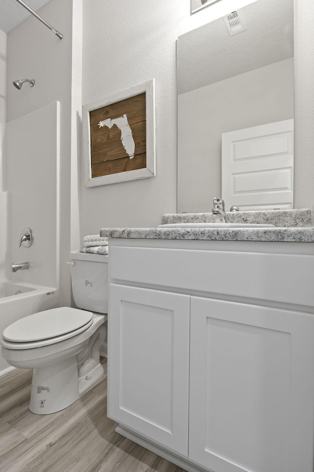 full bathroom featuring hardwood / wood-style floors, toilet, vanity, and shower / washtub combination