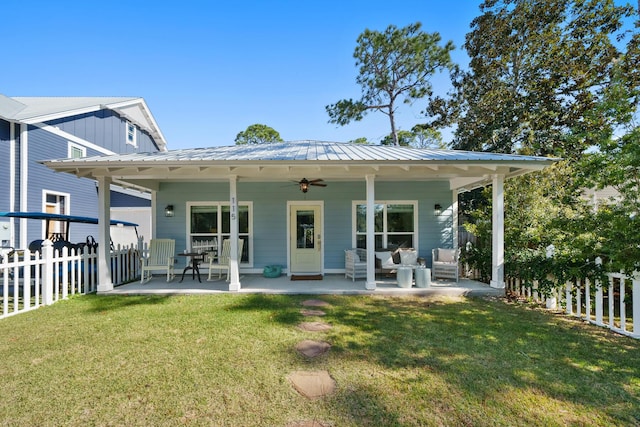 rear view of house with ceiling fan, a lawn, and covered porch