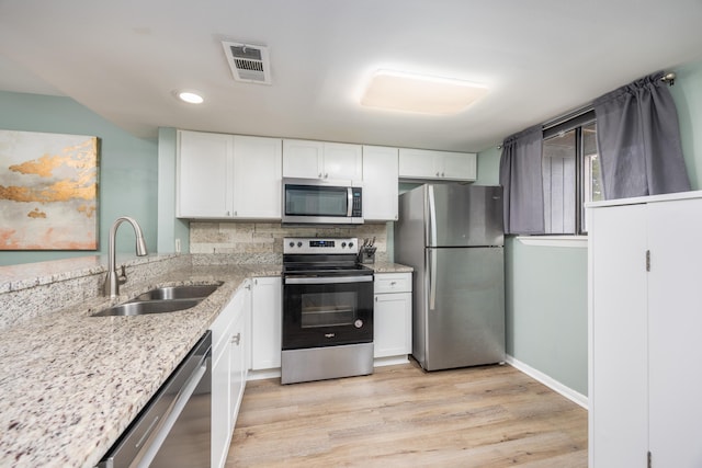 kitchen with white cabinetry, sink, stainless steel appliances, and light hardwood / wood-style flooring