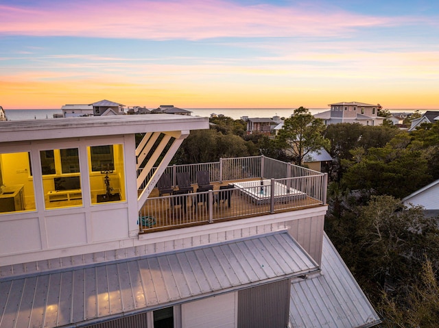 deck at dusk featuring a water view