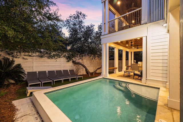 pool at dusk featuring ceiling fan