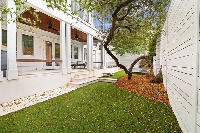 view of yard with ceiling fan, covered porch, and a balcony