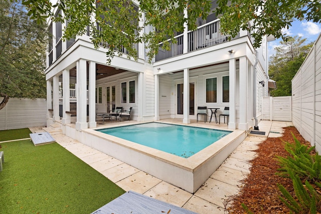 back of house with a fenced in pool, a balcony, and a patio area