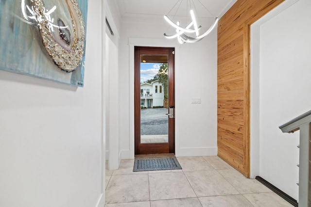 interior space with an inviting chandelier, light tile patterned floors, crown molding, and wooden walls