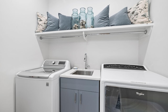 laundry area featuring cabinets, separate washer and dryer, and sink