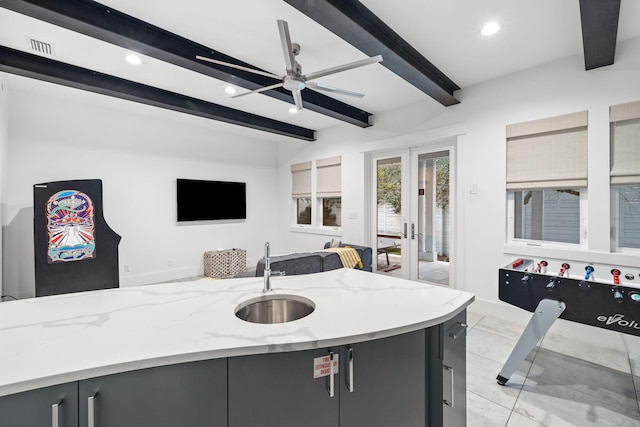 kitchen featuring sink, light stone counters, ceiling fan, beam ceiling, and french doors