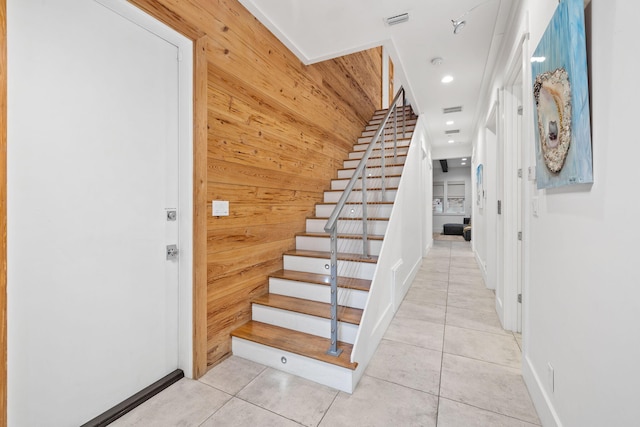 stairway with tile patterned flooring and wooden walls