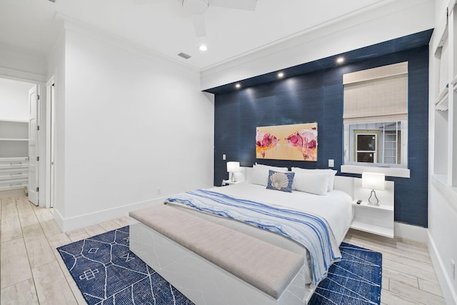 bedroom with hardwood / wood-style floors, ornamental molding, and ceiling fan