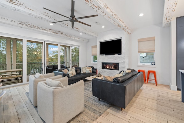 living room featuring ceiling fan, beam ceiling, and a large fireplace