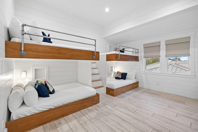 bedroom with light hardwood / wood-style floors and wood walls