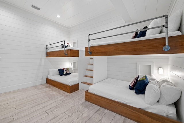 bedroom with wooden walls and light hardwood / wood-style flooring