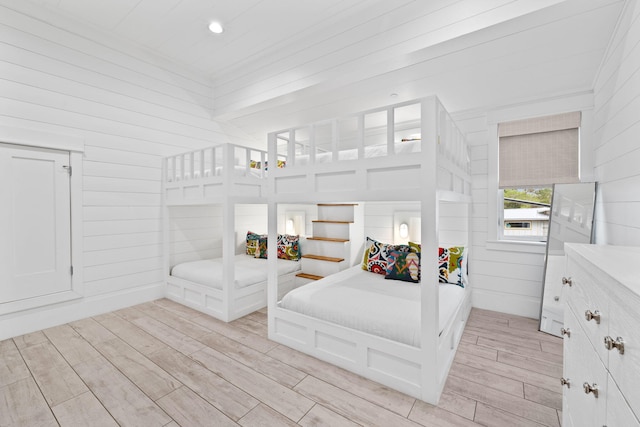 bedroom with light hardwood / wood-style floors and wood walls