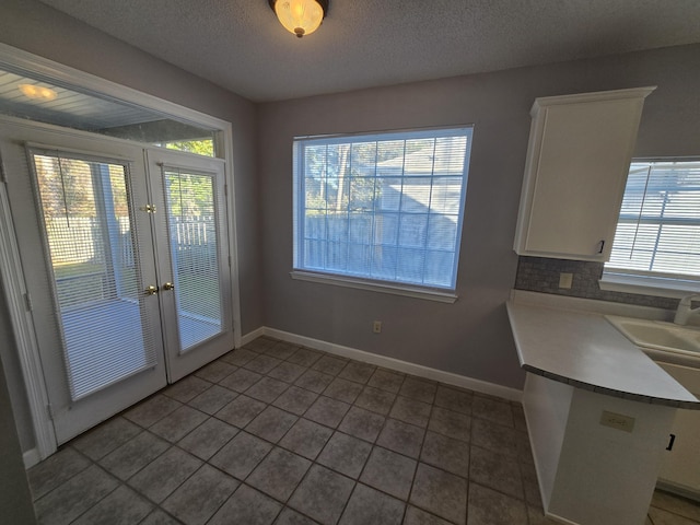 doorway with french doors, a textured ceiling, tile patterned floors, and sink