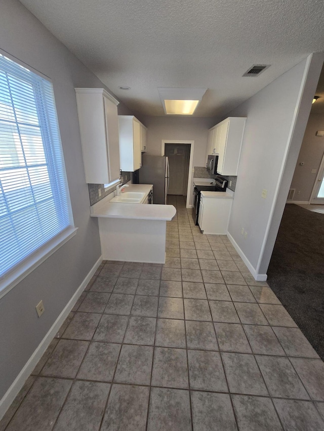 kitchen with white cabinets, sink, tile patterned flooring, kitchen peninsula, and stainless steel appliances