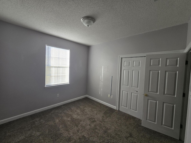 unfurnished bedroom with dark colored carpet, a textured ceiling, and a closet