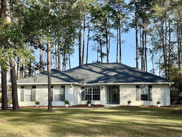 rear view of property featuring a lawn and roof with shingles