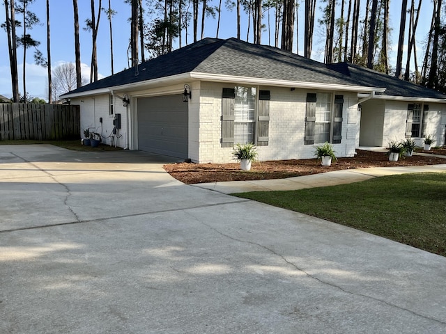 view of front facade featuring brick siding, fence, roof with shingles, a garage, and driveway