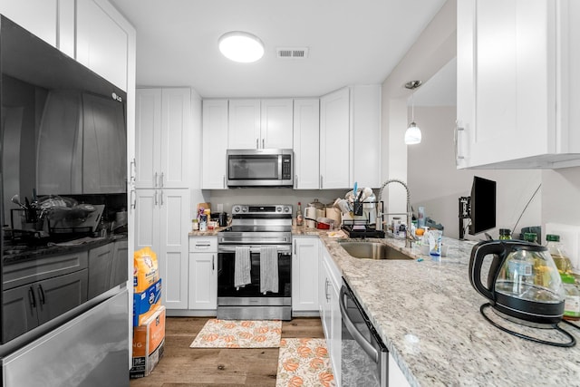 kitchen featuring sink, dark hardwood / wood-style floors, pendant lighting, white cabinets, and appliances with stainless steel finishes