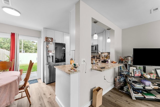 kitchen featuring light stone countertops, white cabinetry, kitchen peninsula, pendant lighting, and appliances with stainless steel finishes