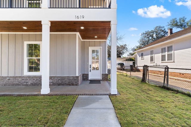 entrance to property featuring a yard and a balcony