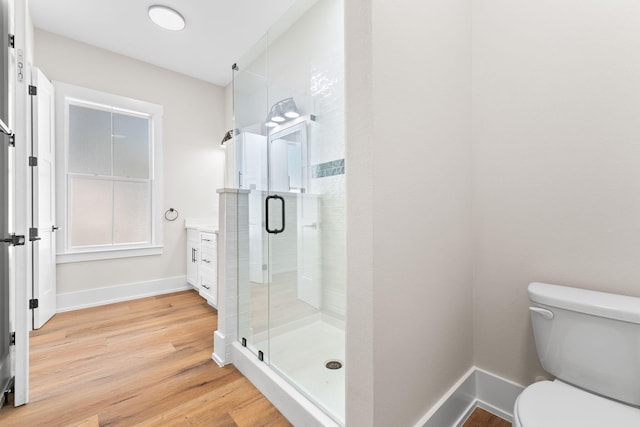 bathroom featuring an enclosed shower, vanity, toilet, and hardwood / wood-style floors