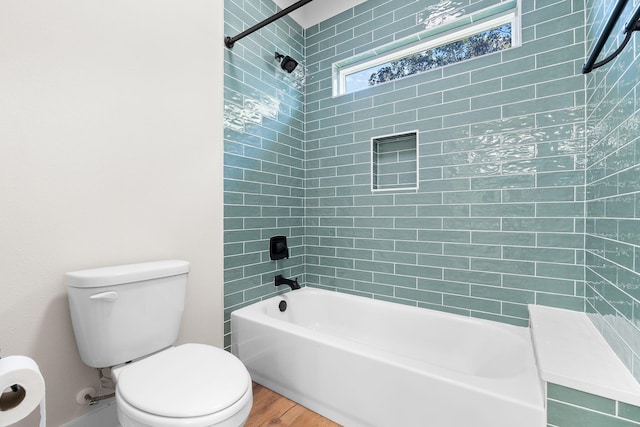 bathroom featuring hardwood / wood-style flooring, toilet, and tiled shower / bath