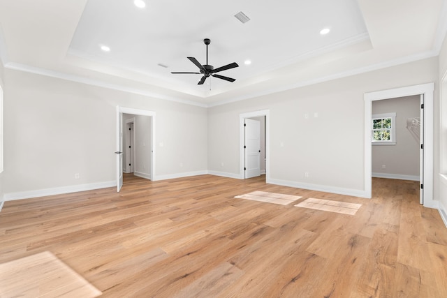 spare room with a tray ceiling, crown molding, light hardwood / wood-style flooring, and ceiling fan