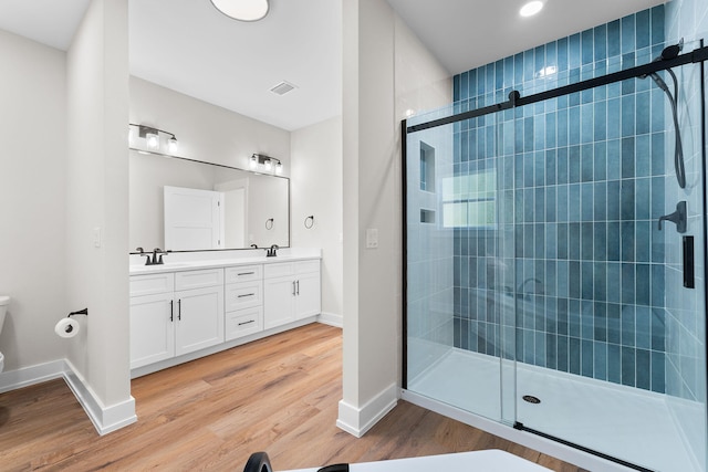 bathroom with wood-type flooring, vanity, and a shower with door