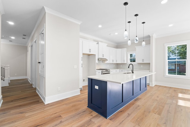 kitchen featuring stainless steel range with gas cooktop, white cabinetry, sink, and a center island with sink