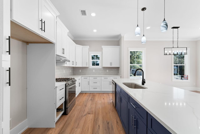 kitchen featuring pendant lighting, white cabinets, blue cabinetry, light stone counters, and stainless steel appliances