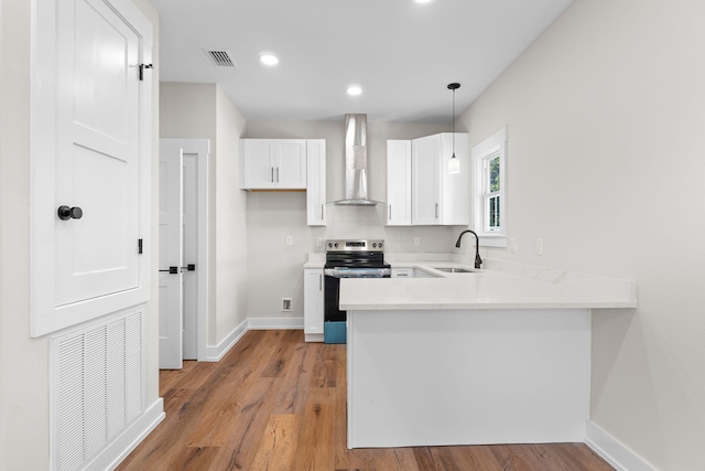 kitchen featuring stainless steel range with electric stovetop, sink, wall chimney range hood, decorative light fixtures, and white cabinets