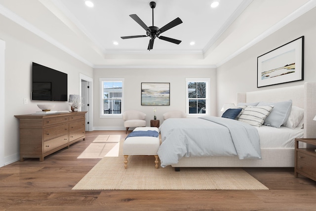 bedroom with a raised ceiling, ceiling fan, crown molding, and wood-type flooring