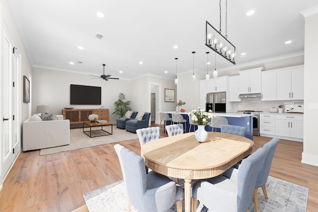 dining space with ceiling fan with notable chandelier, ornamental molding, and light hardwood / wood-style flooring