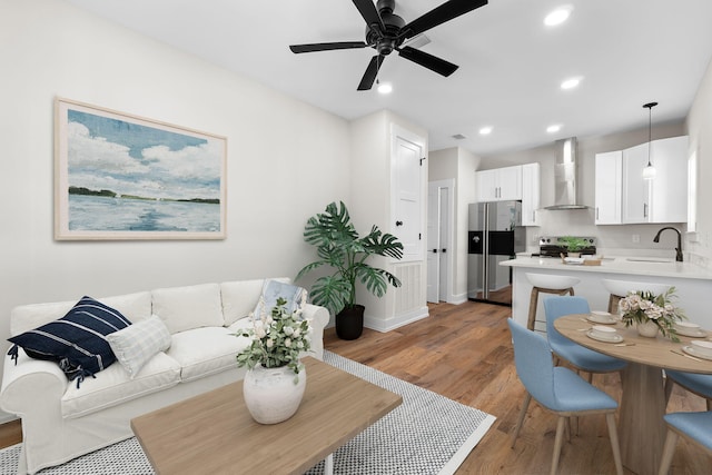 living room with ceiling fan, sink, and wood-type flooring