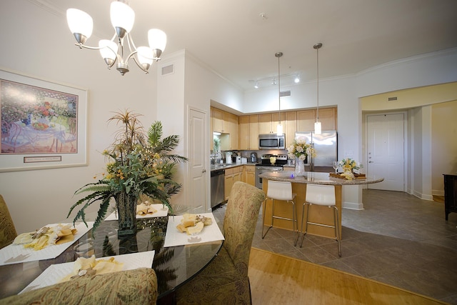 dining area with hardwood / wood-style flooring, a notable chandelier, crown molding, and sink