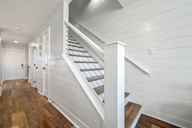 stairway featuring hardwood / wood-style floors and wooden walls