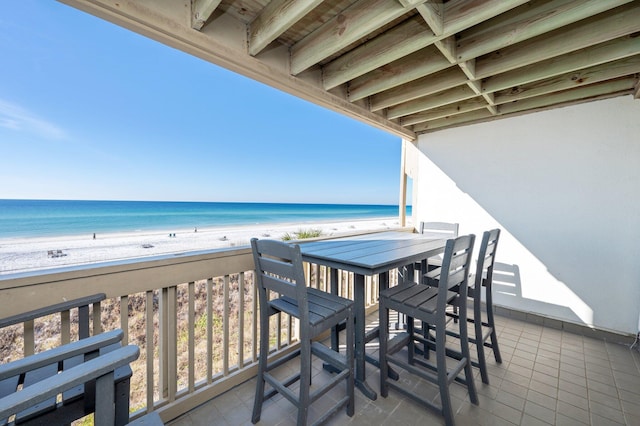 balcony with a water view and a view of the beach