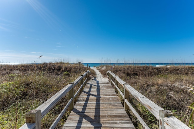 view of dock featuring a beach view and a water view