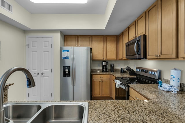 kitchen featuring stone countertops, sink, and stainless steel appliances