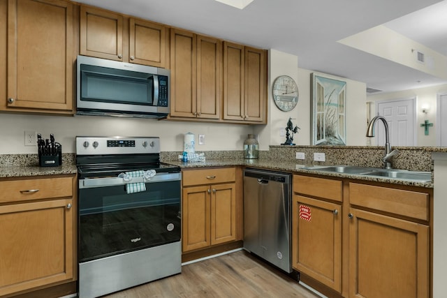 kitchen featuring sink, stainless steel appliances, stone countertops, and light wood-type flooring