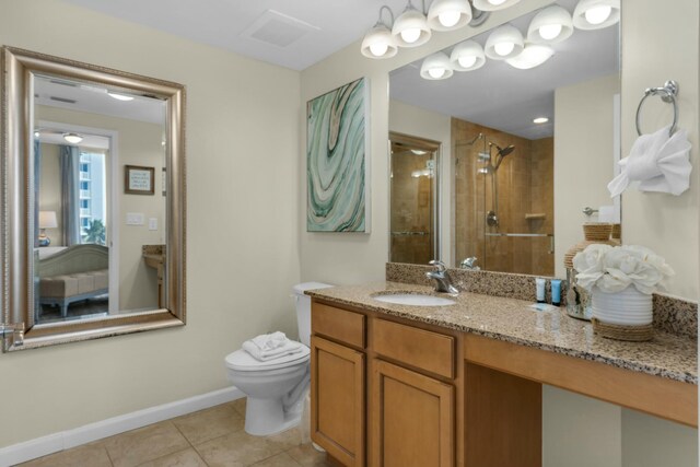 bathroom with toilet, tile patterned flooring, vanity, and tiled shower