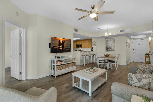 living room featuring ceiling fan with notable chandelier and hardwood / wood-style flooring