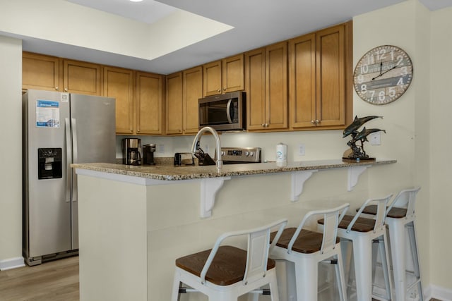 kitchen with a kitchen bar, kitchen peninsula, and appliances with stainless steel finishes