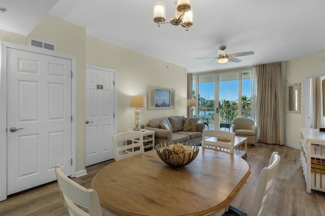 dining room featuring light hardwood / wood-style flooring and ceiling fan with notable chandelier